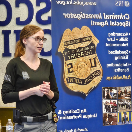 A person speaking in front of a backdrop listing information on the IRS Criminal Investigation unit.